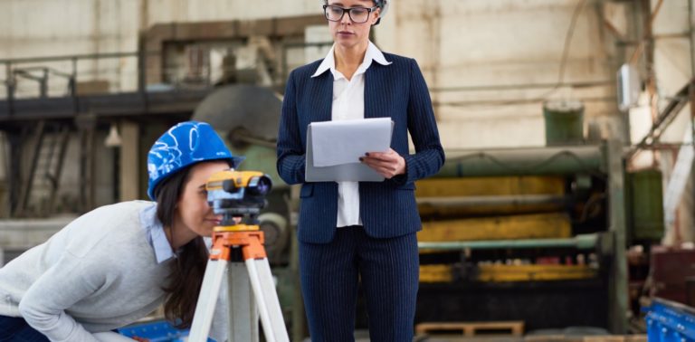 two people surveying in a construction site