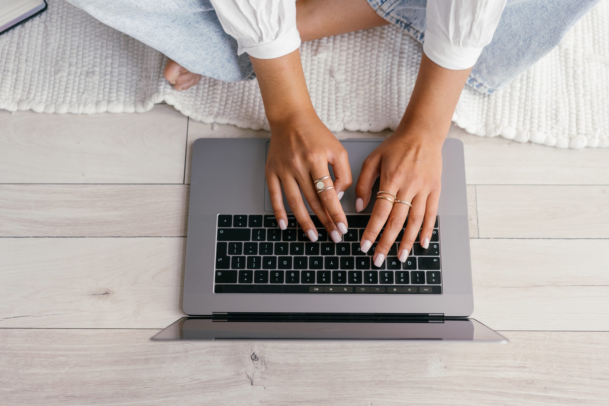 a person criss-crossed on the floor typing on laptop