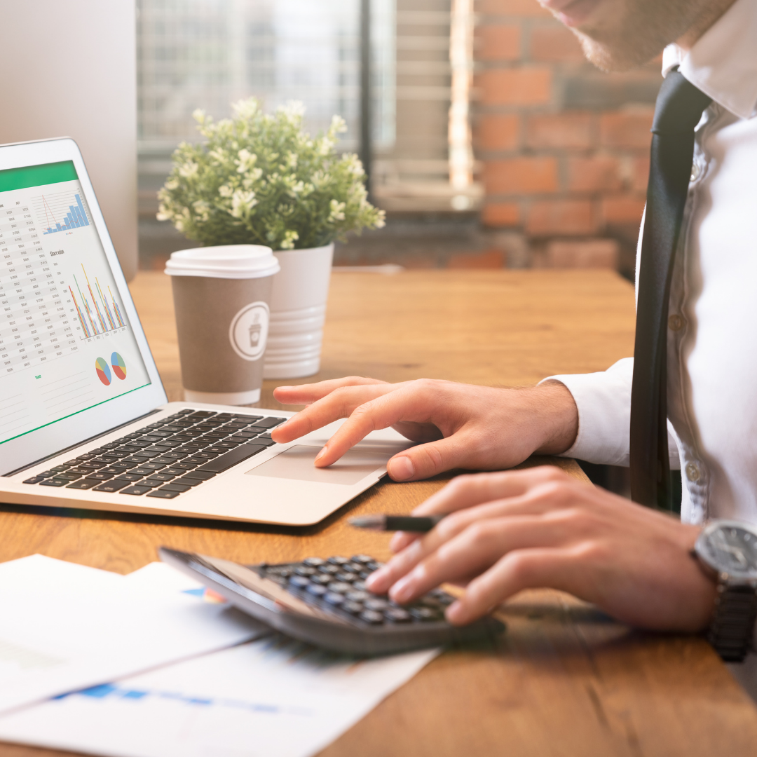 man at desk calculating with laptop and calculator